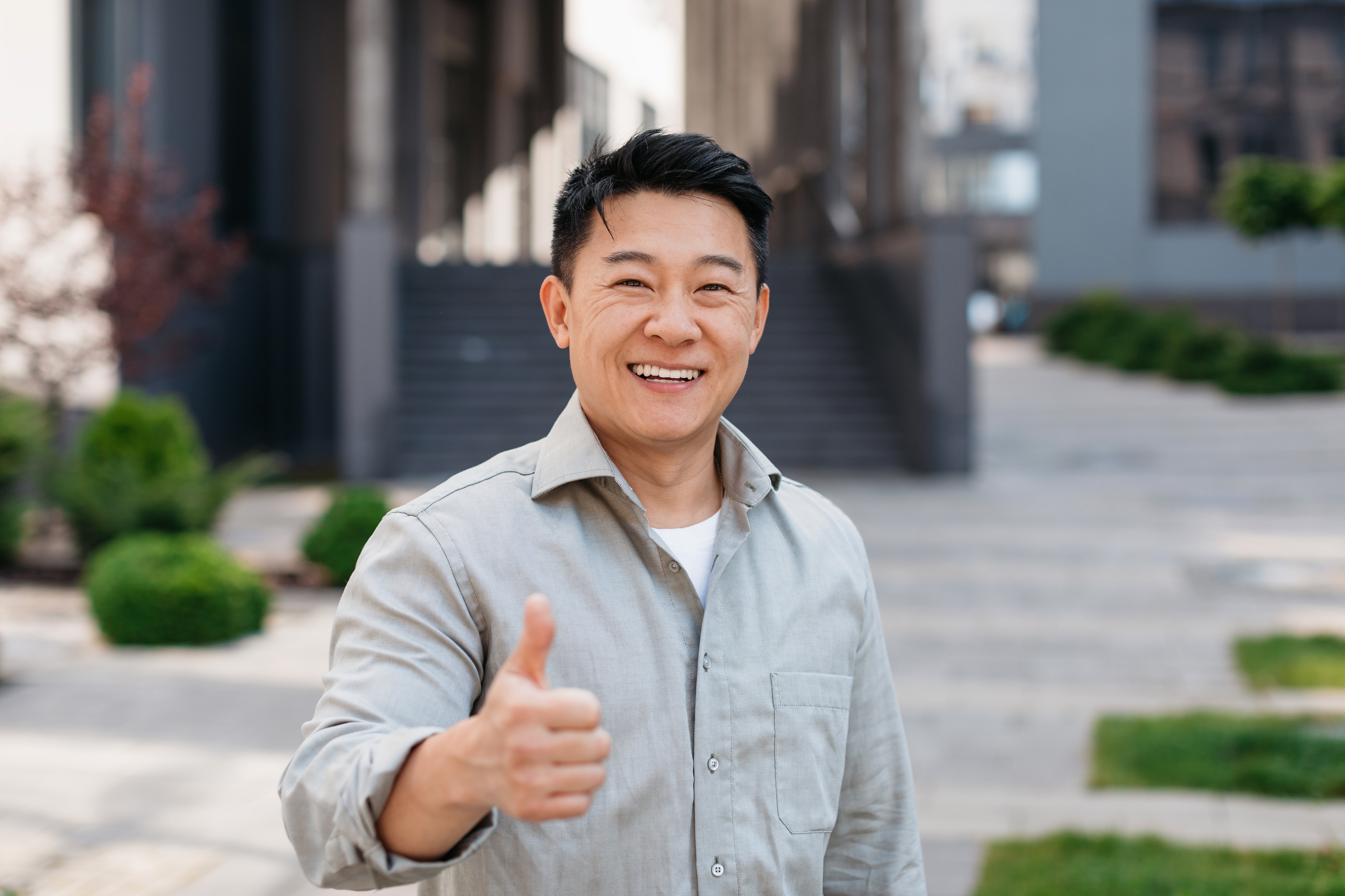 Portrait,Of,Positive,Asian,Man,Standing,Outdoors,And,Gesturing,Thumb