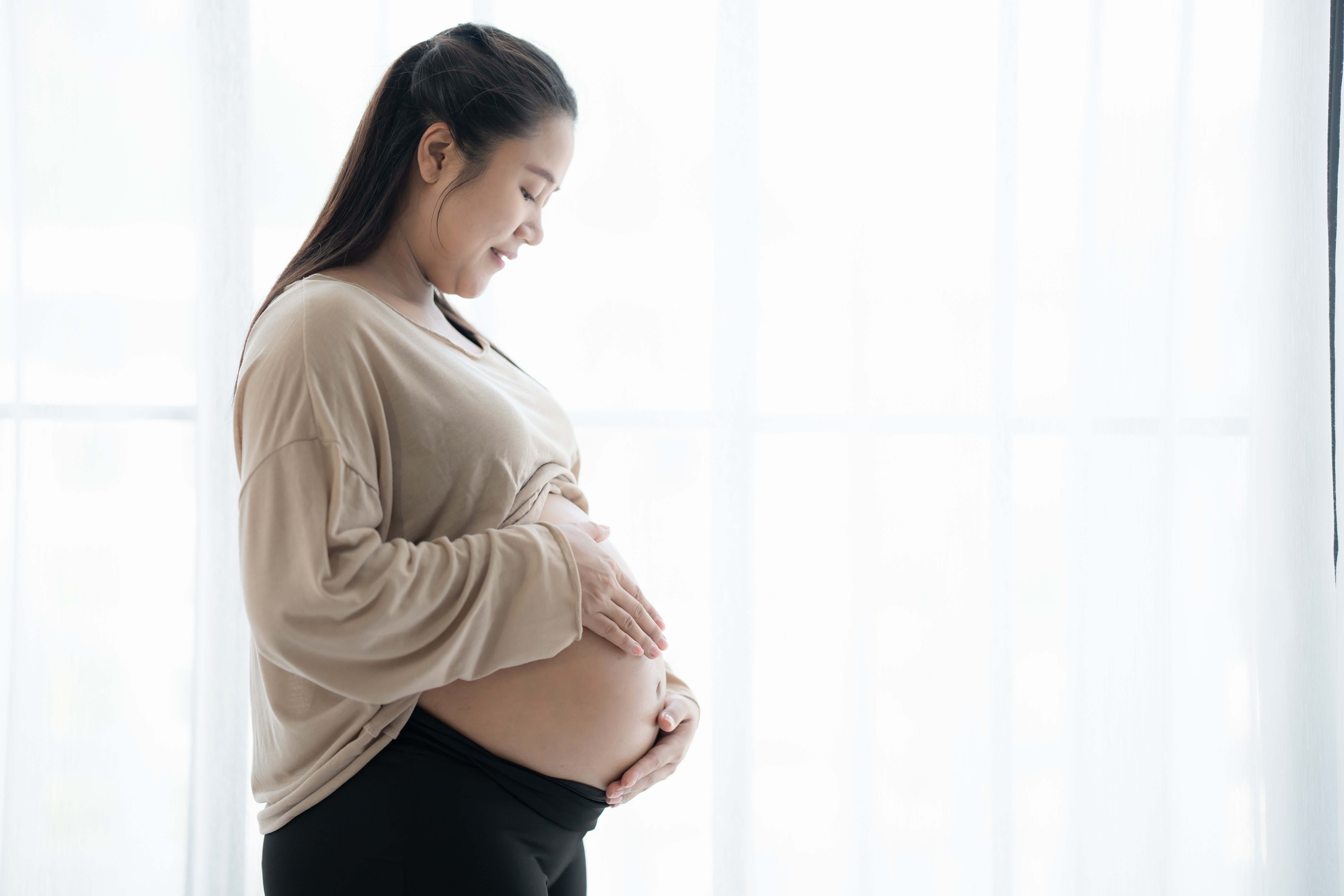 Pregnant,Asian,Woman,Holds,Hands,On,Belly,Touching,Her,Baby